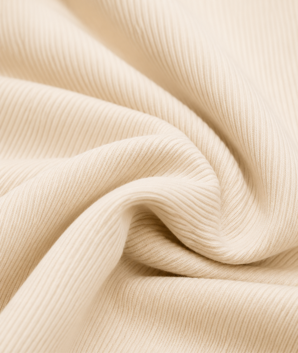 A close-up of cream-colored ribbed fabric with soft folds and a smooth texture.
